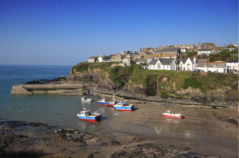 Port Isaac harbour at low tide with boats resting on the sand inside the breakwater