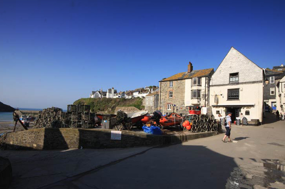 Lobster pots stacked on The Platt beside the harbourside buildings, Port Isaac