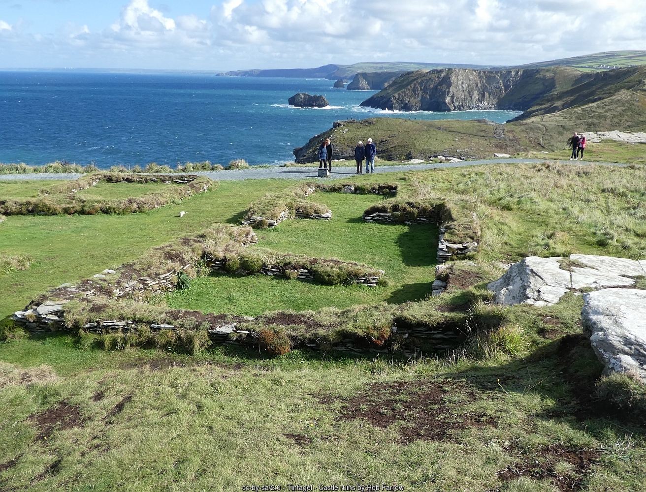 The low walls of ruined buildings on Tintagel Island, with the coast stretching away to the south