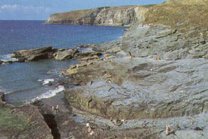 Visitors on the slate rock platform at Trebarwith Strand at low tide