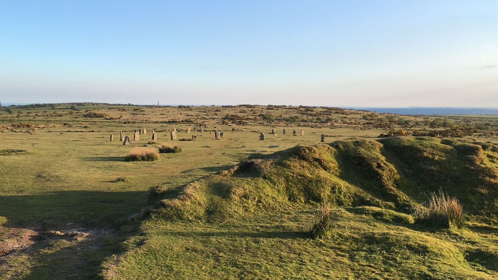 The Hurlers stone circle on Bodmin Moor in the early evening, with old bell pit workings in the foreground
