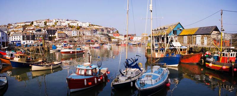 Colourful fishing boats in the inner harbour with the village climbing the hillside behind