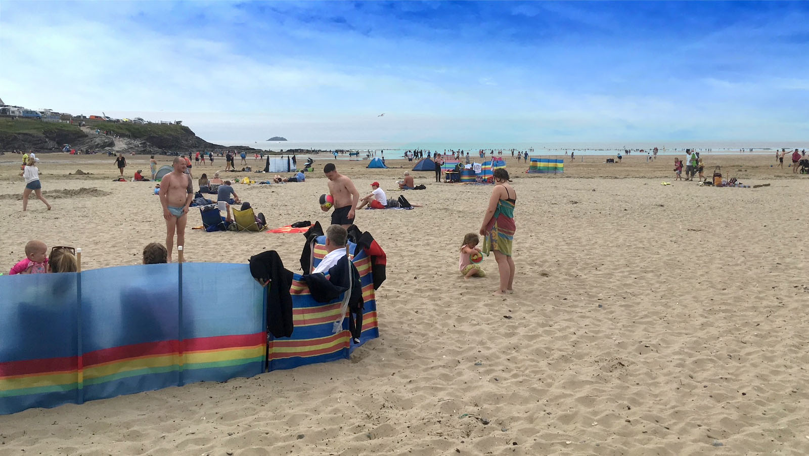 Families with windbreaks enjoying a day on Polzeath beach