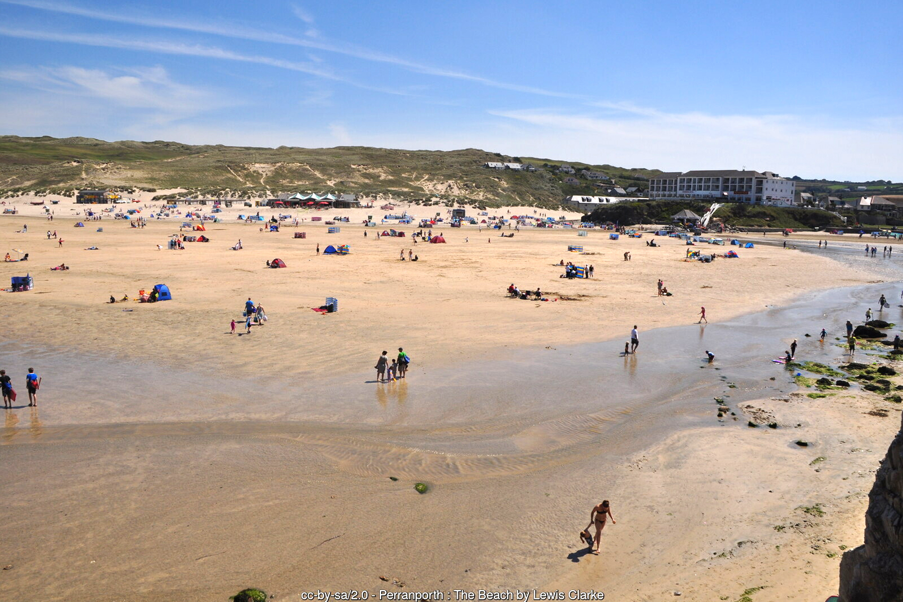 Families relaxing on Perranporth beach beside the stream that runs across the sand
