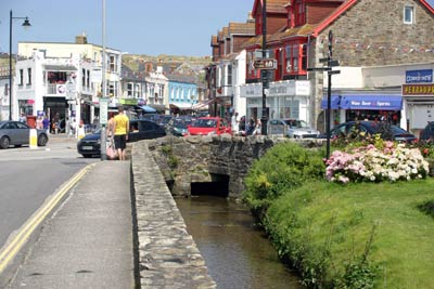 Shops and flowers beside the stream on St Piran&rsquo;s Road, Perranporth